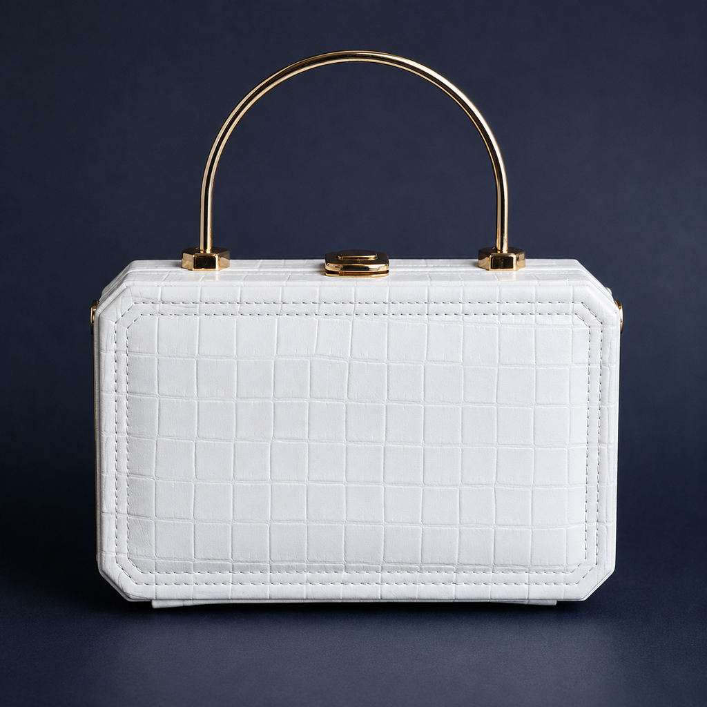 A structured white handbag with an embossed crocodile pattern, featuring a gold-tone arched top handle and a central clasp, set against a dark navy background.