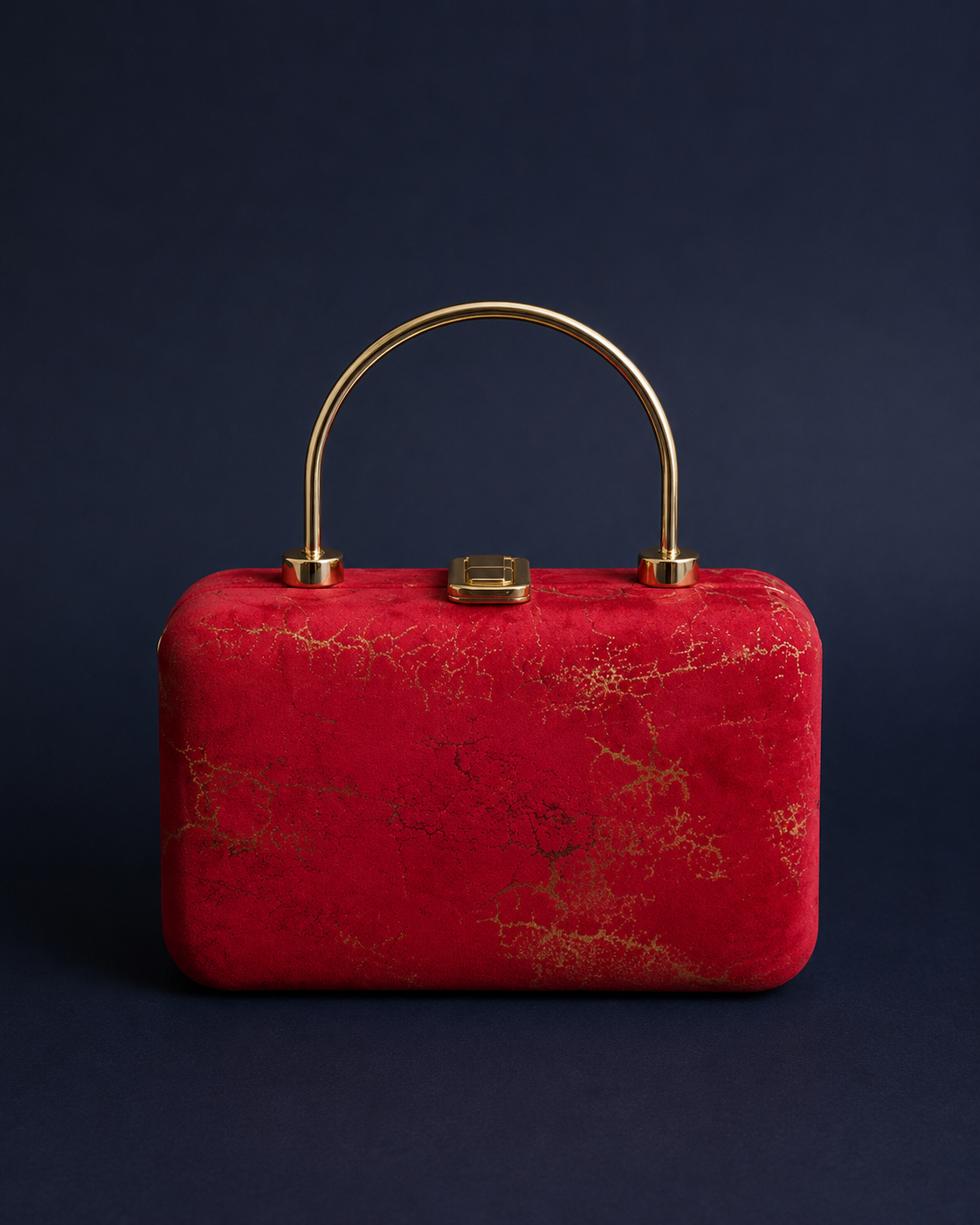 A red textured clutch bag with gold metallic veining and a curved gold metal top handle, set against a dark navy blue background.